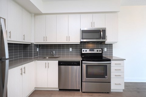 A modern kitchen with white cabinets and stainless steel appliances.