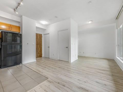 A spacious room with wooden flooring and white walls.