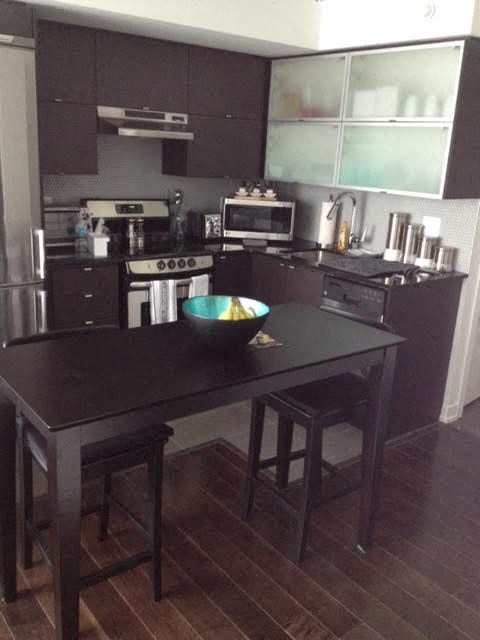 A kitchen with a black table and stools.