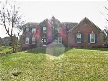 A red brick house with a green lawn in front.