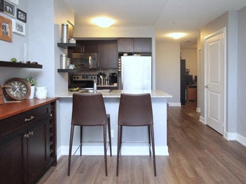 A kitchen with brown chairs and a white fridge.