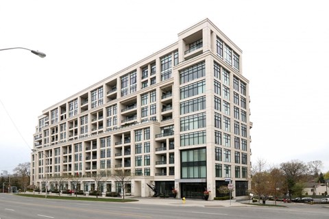 A large, modern building with many windows is situated on a street corner.