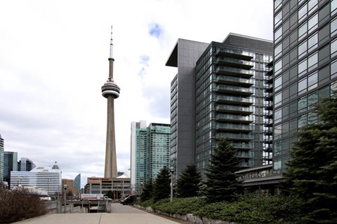 A tall building with a pointed top stands in front of a modern glass building.