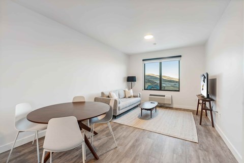 A living room with a round table and chairs, a couch, and a television.