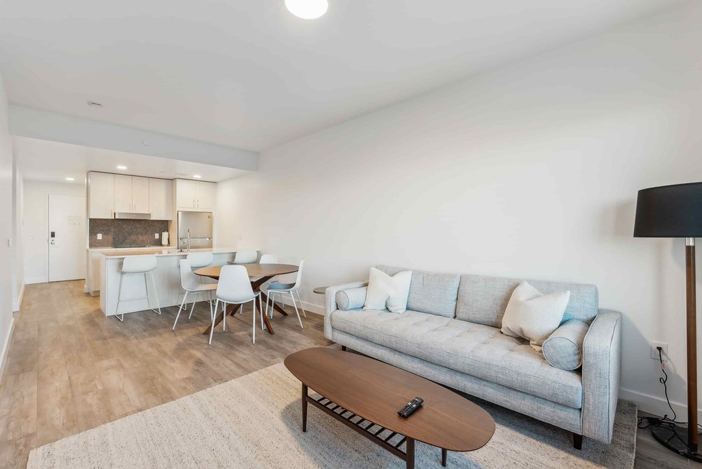 A living room with a grey couch, a coffee table, and a dining table with chairs.