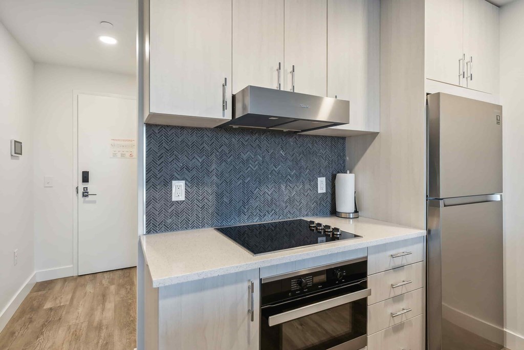 A modern kitchen with a stove top oven and a refrigerator.