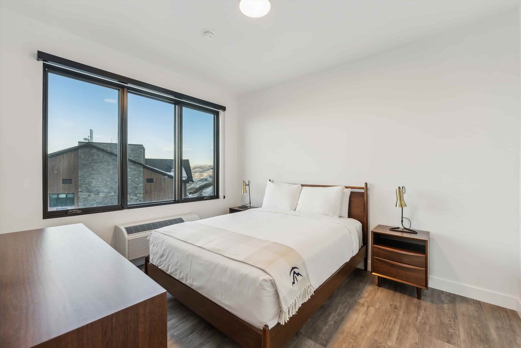 A bedroom with a large bed and a wooden nightstand.