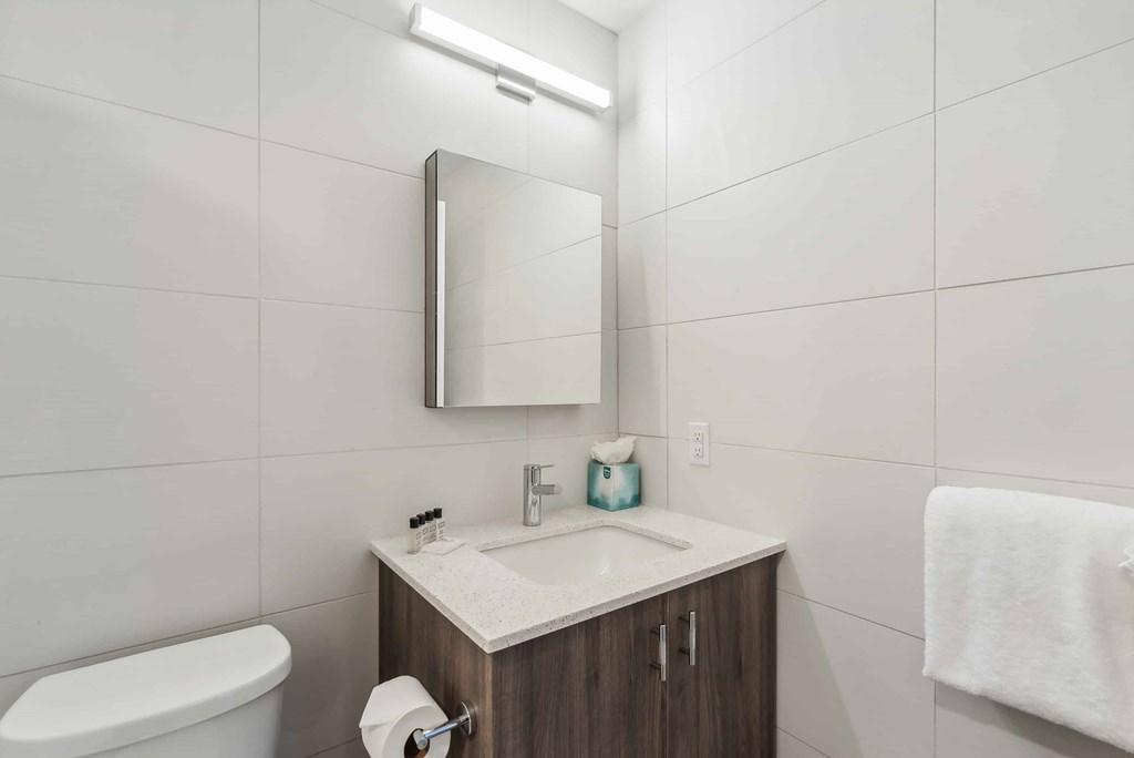 A white bathroom with a toilet, sink, and mirror.