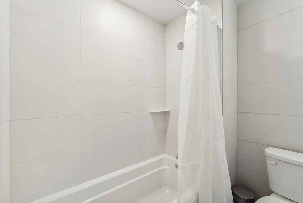 A white bathroom with a toilet and a shower.