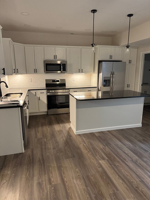 A kitchen with white cabinets and a wooden floor.