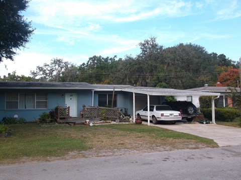 A blue house with a white car parked in front.