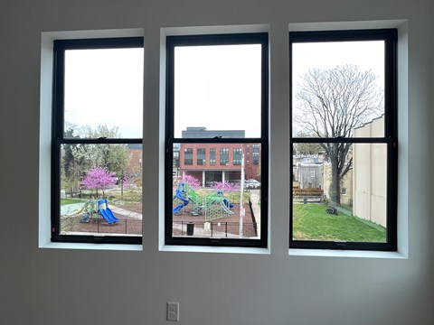 Three windows with different views of a playground, a building, and a tree.