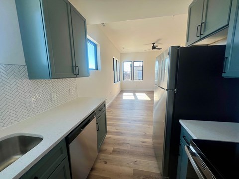 A kitchen with dark green cabinets and a black refrigerator.