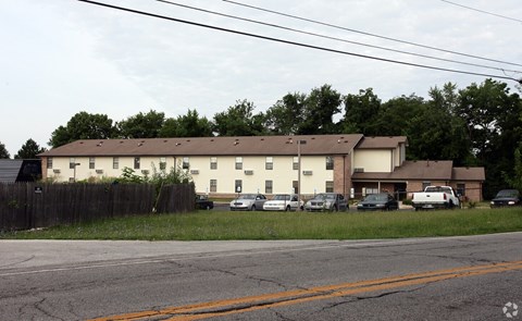 A large white building with a brown roof is surrounded by a wooden fence.