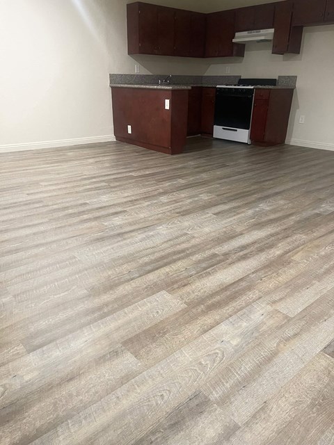 A kitchen with a wooden floor and brown cabinets.