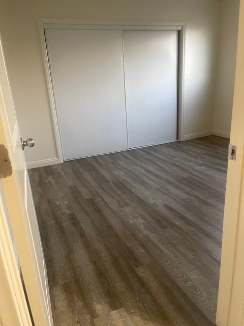 A room with a white door and a wooden floor.