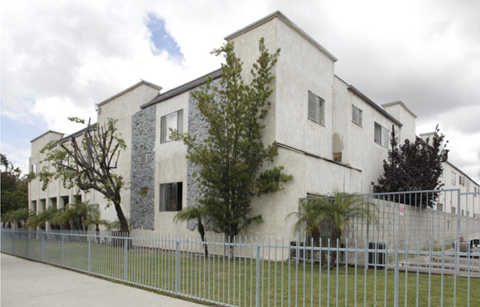 A white building with a grey fence in front.