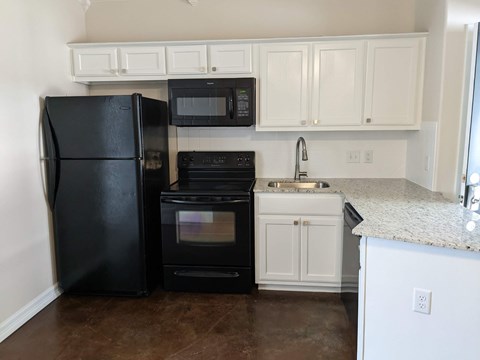 A black refrigerator and oven in a kitchen with white cabinets.