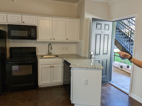 A kitchen with black appliances and white cabinets.