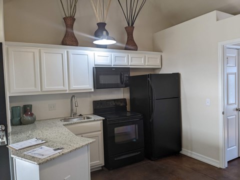 A kitchen with black appliances and white cabinets.