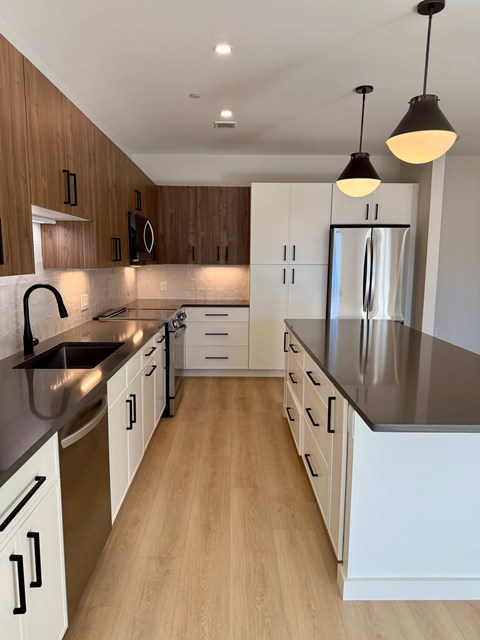 A modern kitchen with wooden cabinets and a stainless steel refrigerator.