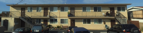 A two-story apartment building with a balcony on the second floor.