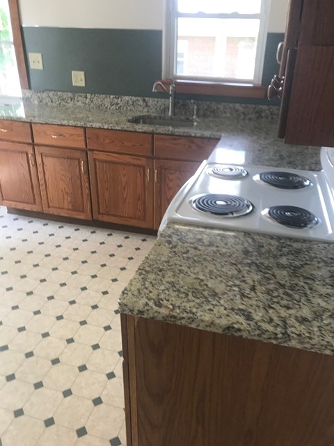 A kitchen with a granite counter top and a tile floor.