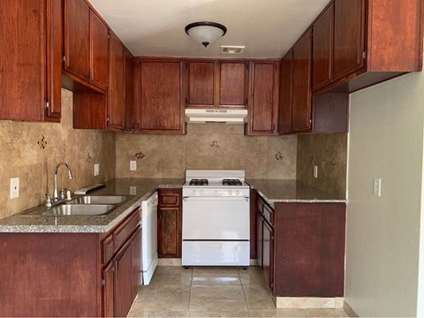 A kitchen with brown cabinets and a white stove.