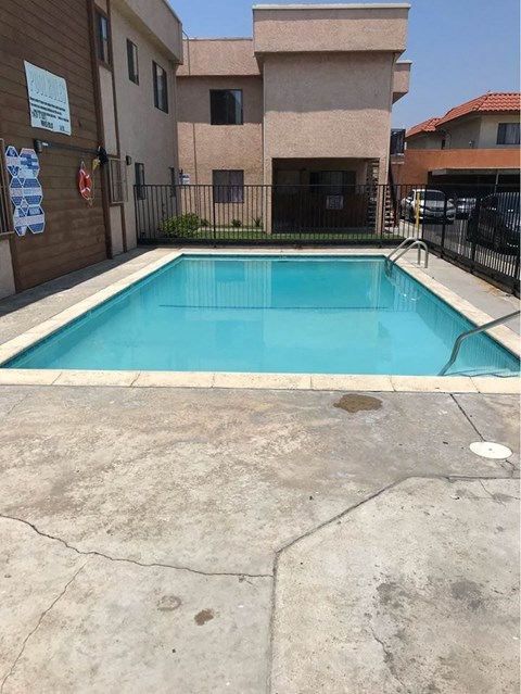 A small pool in a concrete area surrounded by a fence.