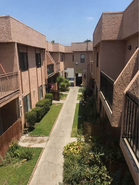A long, narrow walkway separates two rows of apartment buildings.