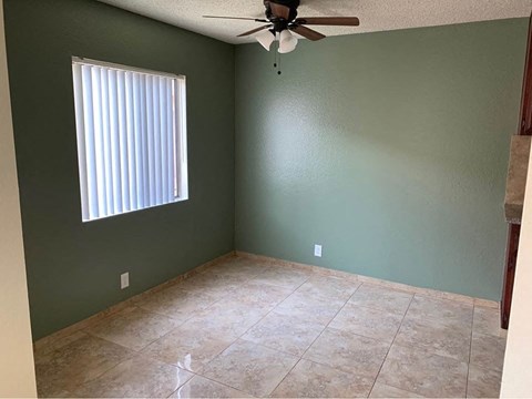 A room with a ceiling fan and a window with blinds.
