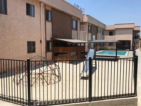 A black fence surrounds a pool and a slide.