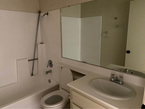 A white bathroom with a toilet, sink, and mirror.