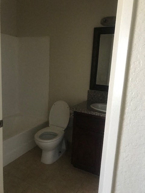 A white toilet sits in a bathroom next to a sink.