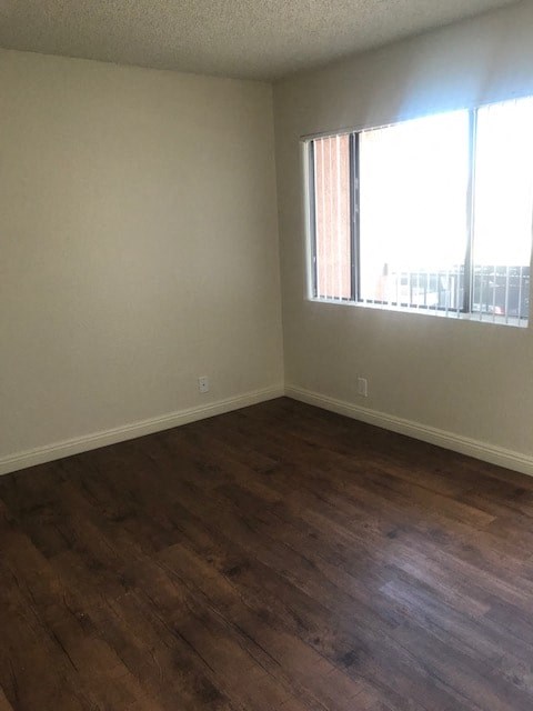 A room with wooden flooring and a window with blinds.