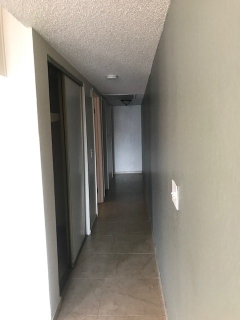 A long hallway with a white ceiling and tiled floor.