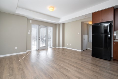 A black refrigerator is in a kitchen with wood floors and white walls.