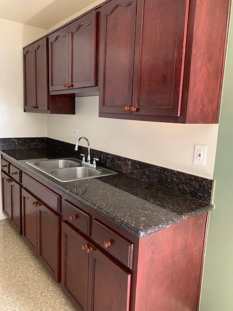 A kitchen with dark wood cabinets and a granite countertop.