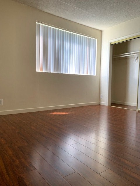 A room with a wooden floor and a window with blinds.