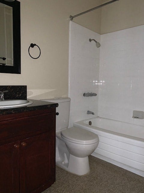 A white toilet sits next to a white bathtub in a bathroom.