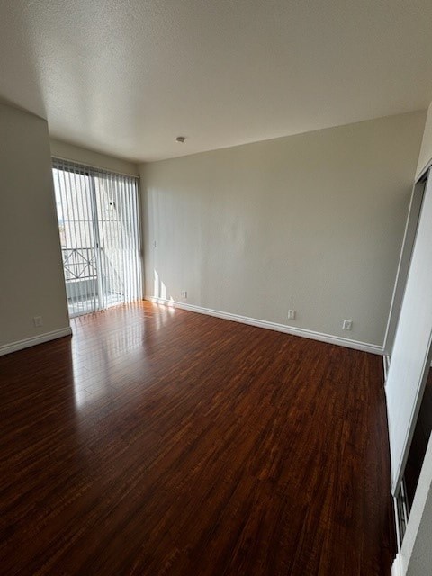 A room with wooden floors and a window with blinds.