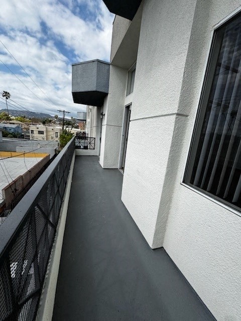 A balcony with a black railing and a white building.