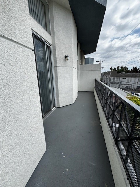 A balcony with a black railing and a white wall.