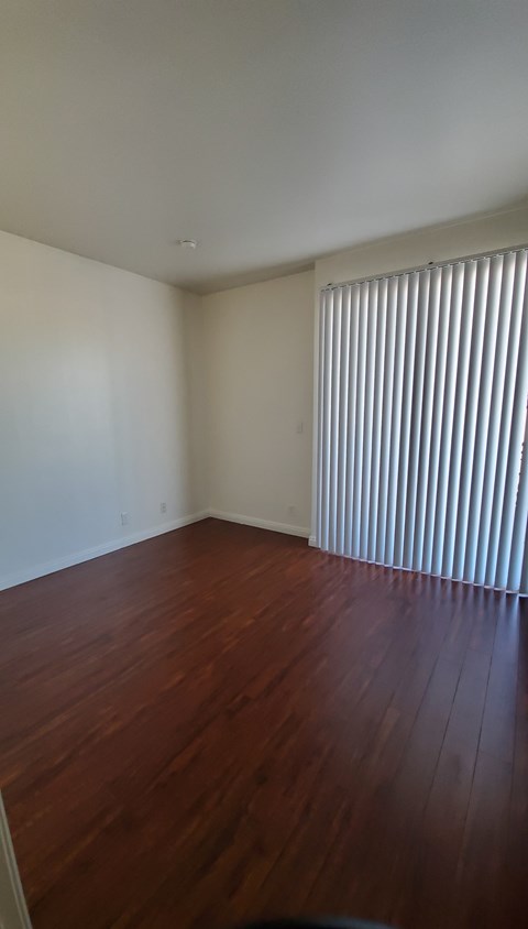 A room with wooden floors and a window with blinds.