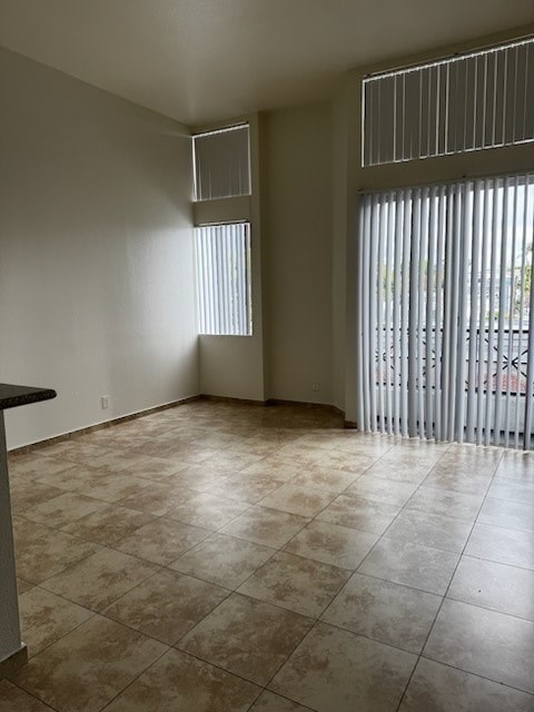A room with tiled flooring and a window with blinds.