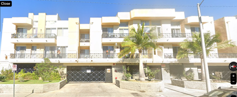 A white apartment building with a black gate in front.