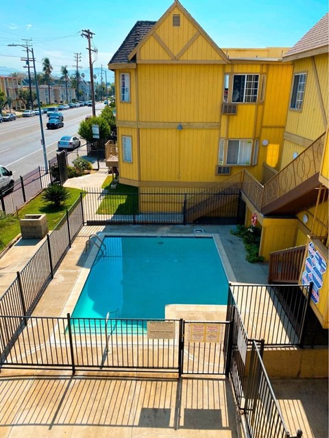 A yellow building with a pool in the backyard.