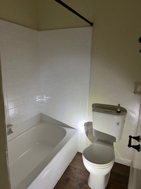 A white toilet in a bathroom with a white tiled wall.