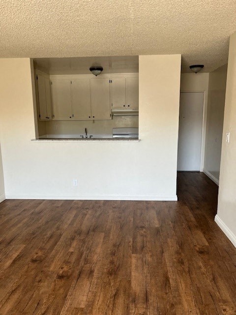 A kitchen with white cabinets and a wooden floor.