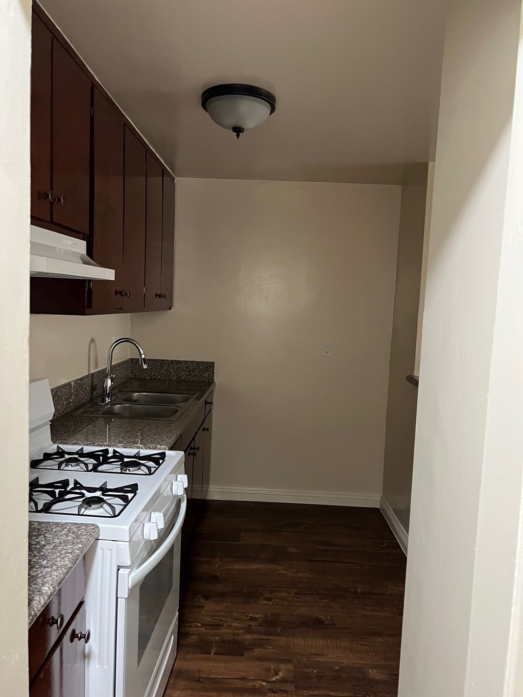A kitchen with a white stove top oven and a sink.